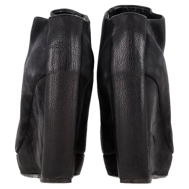 VINTAGE, RRP AS NEW
 Command attention with the Balenciaga Wedge Ankle Boots in black suede, merging sleek sophistication with architectural edge. The sculptural wedge heel and soft suede finish create a bold yet refined silhouette perfect for day-to-night wear. **Style Tip:** Style them with a midi skirt and structured blazer for a chic, contemporary twist on classic tailoring.

Balenciaga Wedge Ankle Boots in Black Suede

Condition: Good
Signs of wear: Moderate signs of wear or markings, moderate scuffing insoles., Used but well maintained. Moderate creasing and marks at surface, wear at soles or replaced soles.
Packaging: None
Color: Black
Material: Suede | suede
Size: IT | 38.5
Measurements: Heel height: 125; Insole length: 255
SKU: BAPUGBSH508323W