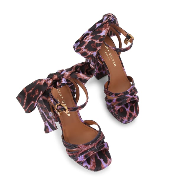 This Brixton Platform is a purple fabric which is embellished with antique brass crystal. There is a silver padlock detail and satin scarf on the ankle straps. Heel height: 11.5cm.