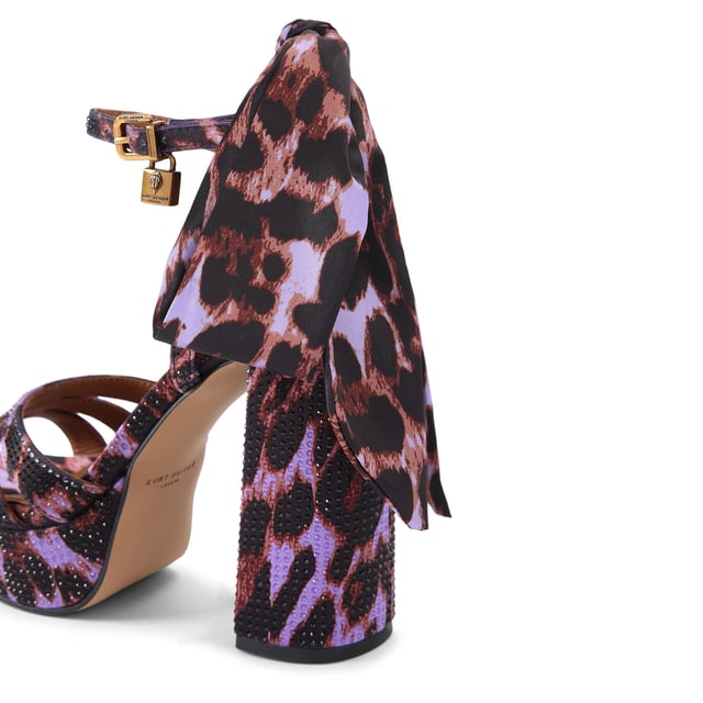 This Brixton Platform is a purple fabric which is embellished with antique brass crystal. There is a silver padlock detail and satin scarf on the ankle straps. Heel height: 11.5cm.