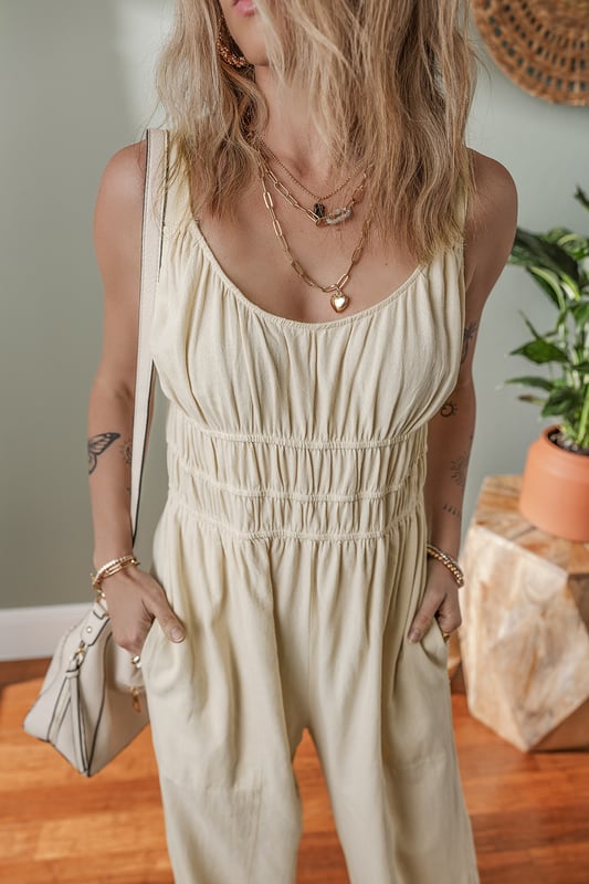 Beige geraffte High-Waist ärmellose weite Jumpsuit  
Flatternde geraffte Details fügen Textur und Dimension hinzu  
Einfarbiges Design bietet endlose Styling-Möglichkeiten  
Das High-Waist-Design definiert die Taille und verlängert die Silhouette  
Ärmellose Silhouette sorgt für ein modernes und luftiges Gefühl  
Material: 100 % Baumwolle