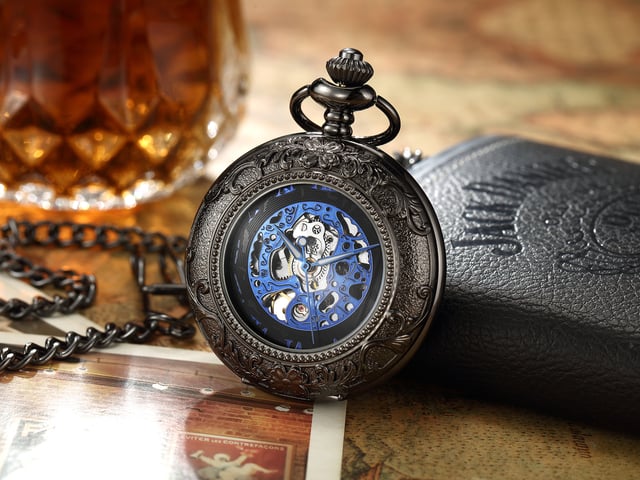 Elegante, mechanische Skelett-Taschenuhr mit Half-Hunter-Gehäuse und Sichtfenster. Inklusive passender Kette und Samtbeutel. Ideal für Sammler, Vintage-Liebhaber oder als unverwechselbares Geschenk. Wichtige Eigenschaften Mechanisches Skelett-Uhrwerk: Präsentiert das komplizierte Innenleben durch sein Skelett-Zifferblatt und bietet ein klassisches mechanisches Aufziehwerk für alle, die traditionelle Handwerkskunst schätzen. Half-Hunter-Gehäusedesign: Verfügt über ein Half-Hunter-Gehäuse mit Sichtfenster, sodass Sie die Uhrzeit ablesen können, ohne die Uhr ganz öffnen zu müssen, während das Zifferblatt vor Kratzern und Staub geschützt ist. Vintage-inspirierte Ästhetik: Mit Details im Antik-Stil verleiht diese Taschenuhr einen Hauch von altmodischem Charme und macht sie zu einem unverwechselbaren Accessoire für formelle Kleidung oder Sammlungszwecke. Passende Kette enthalten: Wird komplett mit einer passenden Kette zur sicheren Befestigung an einer Weste, Gürtelschlaufe oder Tasche geliefert und bietet sowohl Stil als auch Funktionalität. Material: Die Legierungskonstruktion gewährleistet Haltbarkeit und eine zeitlose Ästhetik.