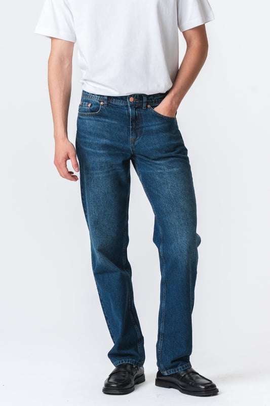 Descubre tu nueva prenda favorita con los jeans Relaxed Fit de TeeShoppen en un azul oscuro profundo y versátil. Imagina la libertad de unos jeans que se sienten tan bien como se ven, de la mañana a la noche.

Experimenta la máxima comodidad y un estilo atemporal.

Nuestros jeans Relaxed Fit están diseñados pensando en tu comodidad. Hechos con 100% algodón puro, estos jeans ofrecen una suavidad excepcional y transpirabilidad que te mantiene fresco todo el día. El azul oscuro es un clásico que nunca pasa de moda y se puede combinar fácilmente para ocasiones formales o informales, según la ocasión.

Hechos para tu día a día: de lo casual a lo elegante.

Ya sea para el trabajo, el ocio o una salida nocturna, estos jeans Relaxed Fit de TeeShoppen son tu aliado de confianza. Su versátil color azul oscuro los hace fáciles de combinar con el resto de tu armario. Combínalos con una camiseta sencilla y zapatillas para un look casual y moderno para todos los días. ¿Necesitas algo un poco más formal? Combínalos con una camisa elegante y unos zapatos de cuero y estarás listo para salir en un instante.

Estos jeans están diseñados para el hombre que quiere verse bien sin necesidad de hacerlo. Su corte holgado te garantiza comodidad sin importar lo que te traiga el día, mientras que el algodón puro deja que tu piel respire. Son el tipo de jeans que usarás una y otra vez porque simplemente funcionan.