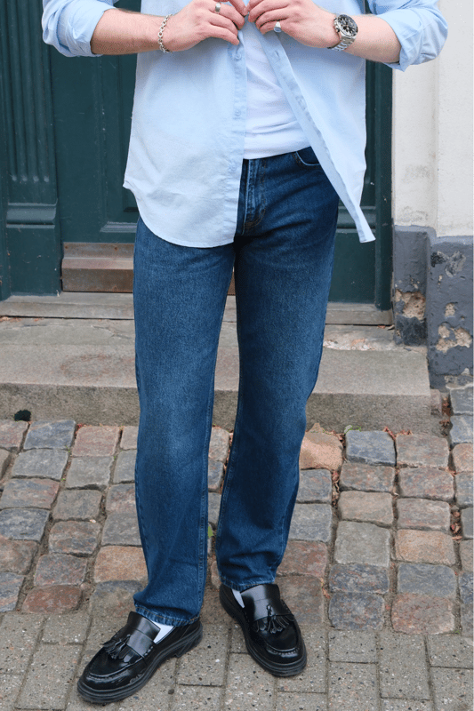 Descubre tu nueva prenda favorita con los jeans Relaxed Fit de TeeShoppen en un azul oscuro profundo y versátil. Imagina la libertad de unos jeans que se sienten tan bien como se ven, de la mañana a la noche.

Experimenta la máxima comodidad y un estilo atemporal.

Nuestros jeans Relaxed Fit están diseñados pensando en tu comodidad. Hechos con 100% algodón puro, estos jeans ofrecen una suavidad excepcional y transpirabilidad que te mantiene fresco todo el día. El azul oscuro es un clásico que nunca pasa de moda y se puede combinar fácilmente para ocasiones formales o informales, según la ocasión.

Hechos para tu día a día: de lo casual a lo elegante.

Ya sea para el trabajo, el ocio o una salida nocturna, estos jeans Relaxed Fit de TeeShoppen son tu aliado de confianza. Su versátil color azul oscuro los hace fáciles de combinar con el resto de tu armario. Combínalos con una camiseta sencilla y zapatillas para un look casual y moderno para todos los días. ¿Necesitas algo un poco más formal? Combínalos con una camisa elegante y unos zapatos de cuero y estarás listo para salir en un instante.

Estos jeans están diseñados para el hombre que quiere verse bien sin necesidad de hacerlo. Su corte holgado te garantiza comodidad sin importar lo que te traiga el día, mientras que el algodón puro deja que tu piel respire. Son el tipo de jeans que usarás una y otra vez porque simplemente funcionan.