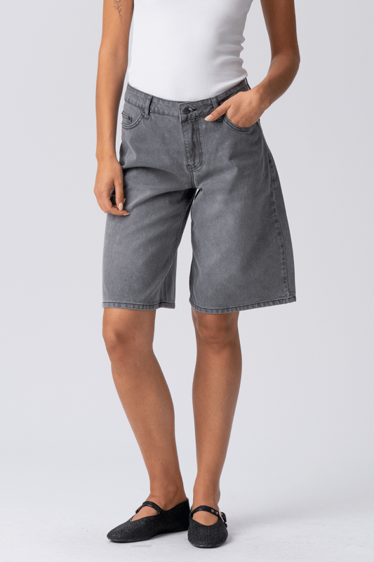 Descubre tu nueva obsesión de verano: Pantalones cortos vaqueros grises

Adéntrate en la frescura sin esfuerzo y la comodidad inigualable de los pantalones cortos vaqueros grises de TeeShoppen, diseñados para la mujer moderna que valora tanto el estilo como la esencia. No son unos shorts vaqueros cualquiera; son tu próxima prenda básica, listas para disfrutar de aventuras soleadas, fines de semana relajados y todo lo demás. Imagina una prenda versátil que combina a la perfección un estilo moderno con la comodidad para el día a día: esa es la promesa de nuestros pantalones cortos vaqueros grises, elaborados meticulosamente.

Experimenta una comodidad inigualable: Confeccionados con 100 % algodón puro

Los pantalones cortos vaqueros grises de TeeShoppen están diseñados pensando en la silueta femenina. Su corte es moderno y atemporal, con un largo favorecedor, práctico y elegante. Cubren para mayor comodidad y realzan las piernas, logrando el equilibrio perfecto para un look veraniego chic. El diseño clásico de los pantalones cortos presenta detalles esenciales como bolsillos funcionales y un cierre seguro, combinando moda y practicidad.