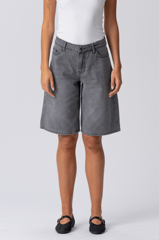 Descubre tu nueva obsesión de verano: Pantalones cortos vaqueros grises

Adéntrate en la frescura sin esfuerzo y la comodidad inigualable de los pantalones cortos vaqueros grises de TeeShoppen, diseñados para la mujer moderna que valora tanto el estilo como la esencia. No son unos shorts vaqueros cualquiera; son tu próxima prenda básica, listas para disfrutar de aventuras soleadas, fines de semana relajados y todo lo demás. Imagina una prenda versátil que combina a la perfección un estilo moderno con la comodidad para el día a día: esa es la promesa de nuestros pantalones cortos vaqueros grises, elaborados meticulosamente.

Experimenta una comodidad inigualable: Confeccionados con 100 % algodón puro

Los pantalones cortos vaqueros grises de TeeShoppen están diseñados pensando en la silueta femenina. Su corte es moderno y atemporal, con un largo favorecedor, práctico y elegante. Cubren para mayor comodidad y realzan las piernas, logrando el equilibrio perfecto para un look veraniego chic. El diseño clásico de los pantalones cortos presenta detalles esenciales como bolsillos funcionales y un cierre seguro, combinando moda y practicidad.
