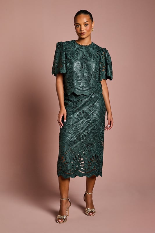Luxurious PU midi skirt featuring intricate lace overlay with botanical pattern
        Elegant scalloped hem detail adds a refined finishing touch
        Figure-flattering silhouette with a sophisticated midi length
        Designed specifically for petite frames for perfect proportions
        Semi-sheer lace detailing creates a striking textural contrast
    
    This exquisite Petite PU Lace Midi Skirt from Coast combines contemporary style with timeless elegance. The striking botanical lace overlay creates a captivating visual texture whilst the scalloped hem adds a touch of femininity to this sophisticated piece. Perfect for special occasions, this skirt pairs beautifully with a simple silk camisole and strappy metallic heels as shown for a wedding guest ensemble that commands attention. For race day events, complement with a tailored blazer and fascinator for a look that balances tradition with modern flair. The midi length is particularly flattering on petite frames, whilst the PU fabrication offers structure and durability. This versatile piece transitions effortlessly from formal daytime events to evening soires, making it a valuable addition to your occasion wardrobe.