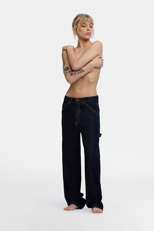 Locker geschnittenes Jeansmodell für Frauen, inspiriert von der Arbeitshose für Männer. Maxi-Seitentaschen, Hammerschlaufe und fließende Stoffe in tiefblauer Waschung, die auch am Abend getragen werden können.
