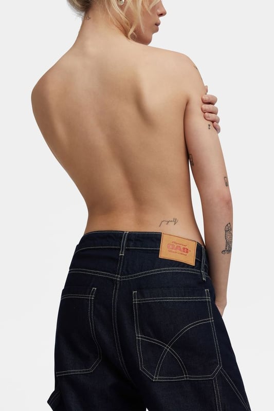 Locker geschnittenes Jeansmodell für Frauen, inspiriert von der Arbeitshose für Männer. Maxi-Seitentaschen, Hammerschlaufe und fließende Stoffe in tiefblauer Waschung, die auch am Abend getragen werden können.
