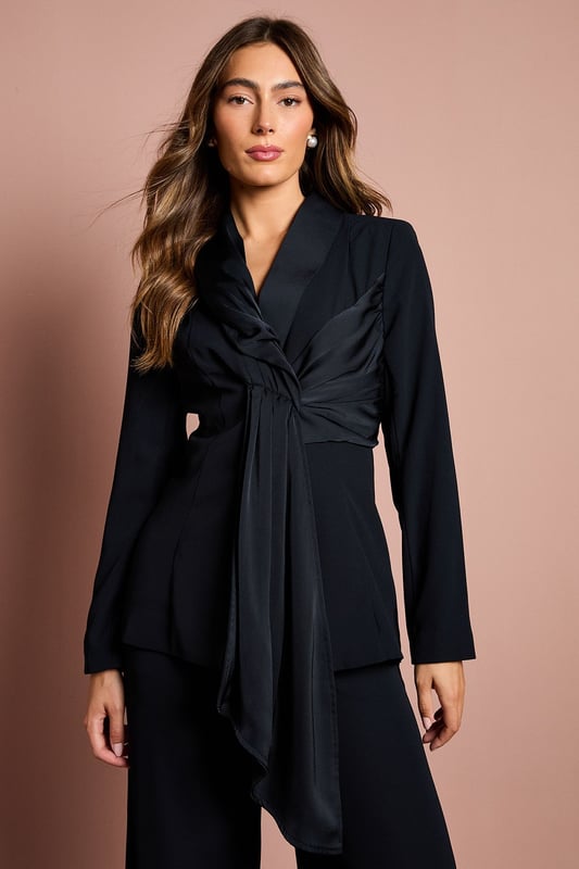 Elegant crepe blazer featuring a sophisticated drape front detail with luxurious satin trim
        Distinctive collared neckline creates a refined silhouette perfect for special occasions
        Flattering gathered waist design enhances your natural shape
        Long sleeves with structured shoulders for a polished, tailored appearance
        Versatile piece that transitions effortlessly from day to evening events
    
    Make a striking entrance at your next special occasion with this beautifully crafted Coast blazer. The standout drape front detail with satin trim creates a graceful cascade effect that adds movement and sophistication to your ensemble. Pair with the matching wide-leg trousers as shown for a contemporary take on occasion dressing that will turn heads at weddings, race days or graduation ceremonies. The structured shoulders and tailored fit create a flattering silhouette, whilst the crepe fabric offers a luxurious drape that moves elegantly with you. Complete your look with statement earrings and pointed heels for the ultimate in refined style. This versatile piece works beautifully as part of a coordinated set or can be styled with slim trousers and a camisole for a more relaxed yet equally chic approach to formal dressing.