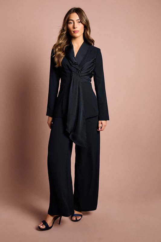 Elegant crepe blazer featuring a sophisticated drape front detail with luxurious satin trim
        Distinctive collared neckline creates a refined silhouette perfect for special occasions
        Flattering gathered waist design enhances your natural shape
        Long sleeves with structured shoulders for a polished, tailored appearance
        Versatile piece that transitions effortlessly from day to evening events
    
    Make a striking entrance at your next special occasion with this beautifully crafted Coast blazer. The standout drape front detail with satin trim creates a graceful cascade effect that adds movement and sophistication to your ensemble. Pair with the matching wide-leg trousers as shown for a contemporary take on occasion dressing that will turn heads at weddings, race days or graduation ceremonies. The structured shoulders and tailored fit create a flattering silhouette, whilst the crepe fabric offers a luxurious drape that moves elegantly with you. Complete your look with statement earrings and pointed heels for the ultimate in refined style. This versatile piece works beautifully as part of a coordinated set or can be styled with slim trousers and a camisole for a more relaxed yet equally chic approach to formal dressing.