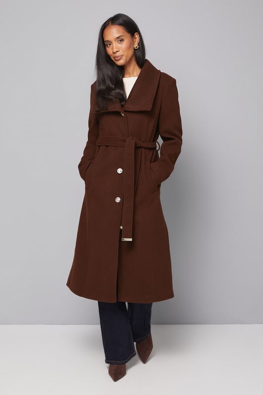 Elegant knitted collar for added sophistication
        Wrap design with button-through closure for versatile styling
        Long length offers maximum coverage and warmth
        Belted waist creates a flattering silhouette
        Functional side pockets for practicality
    
    This Wallis Knitted Collar Button Through Wrap Coat is the epitome of refined elegance. Perfect for the woman who appreciates sophistication without compromising on comfort, this coat is a versatile addition to any wardrobe. The wrap design allows for customisable fit, while the button-through closure adds a touch of classic charm. Style it over a sleek midi dress and pair with heeled boots for a polished look at formal events. For smart casual occasions, layer it over tailored trousers and a fine knit jumper, completing the ensemble with leather ankle boots. The long length and belted waist not only provide warmth but also create a striking silhouette that's sure to turn heads. Whether you're attending a business meeting or heading to a sophisticated dinner, this coat will ensure you look impeccably put-together while feeling effortlessly comfortable.