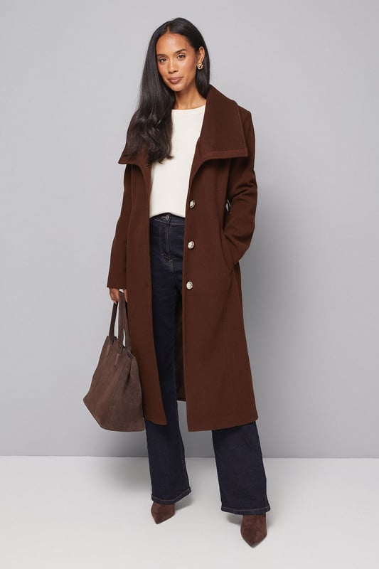 Elegant knitted collar for added sophistication
        Wrap design with button-through closure for versatile styling
        Long length offers maximum coverage and warmth
        Belted waist creates a flattering silhouette
        Functional side pockets for practicality
    
    This Wallis Knitted Collar Button Through Wrap Coat is the epitome of refined elegance. Perfect for the woman who appreciates sophistication without compromising on comfort, this coat is a versatile addition to any wardrobe. The wrap design allows for customisable fit, while the button-through closure adds a touch of classic charm. Style it over a sleek midi dress and pair with heeled boots for a polished look at formal events. For smart casual occasions, layer it over tailored trousers and a fine knit jumper, completing the ensemble with leather ankle boots. The long length and belted waist not only provide warmth but also create a striking silhouette that's sure to turn heads. Whether you're attending a business meeting or heading to a sophisticated dinner, this coat will ensure you look impeccably put-together while feeling effortlessly comfortable.