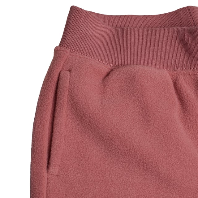 Plüschhose mit weitem Bein für Mädchen, ideal für entspannte Momente.\n\n Diese langen Hosen #M1 für Mädchen vereinen Weichheit und lässigen Stil in einem bequemen Alltagsstück. Ihr gerader Schnitt und der weiche Stoff machen sie perfekt zum Faulenzen zu Hause oder für lässige Ausflüge mit einem gemütlichen Touch.\n\n Details:\n Art des Kleidungsstücks: Lange Hosen für Mädchen.\n Design: Ausgestelltes Bein mit aufgesticktem Logo oben.\n Taille: Elastisch, kein sichtbarer Kordelzug.\n Verschluss: Kein Verschluss, zum Überziehen.\n Taschen: Funktionelle Seitentaschen.\n Material: Weicher und warmer Plüsch.\n Passform: Lockere Passform, für alltäglichen Komfort konzipiert.\n\n Vielseitige und warme Mädchenhosen, ideal, um Komfort zu genießen, ohne auf Stil zu verzichten.\n Komposition: 100% Polyester\n Pflege:\nMaschinenwäsche in kaltem Wasser.\n Verwenden Sie kein Bleichmittel.\n An der Luft trocknen.\n Reinige chemisch nicht.