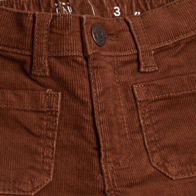 Schlaghose aus Cord für Mädchen im Retro-Stil und mit weicher Textur.\n\n Diese GAP Mädchenhose kombiniert ein Vintage-inspiriertes Design mit der Wärme und Weichheit von Cord. Ihre Vordertaschen und der ausgestellte Schnitt machen sie bequem und stilvoll für den Alltag.\n\n Details:\n Art des Kleidungsstücks: Lange Hosen für Mädchen.\n Design: Ausgestelltes Bein mit aufgesetzten Taschen vorne.\n Taille: Gummizug hinten mit Gürtelschlaufen.\n Verschluss: Reißverschluss.\n Material: Weicher und strapazierfähiger Cordstoff.\n Passform: Bequem, mit weitem Beinausschnitt ab dem Knie.\n\n Eine Mädchenhose mit Retro-Touch, ideal für originelle und gemütliche Looks zu jeder Jahreszeit.\n Komposition: 98 % Baumwolle, 2 % Elasthan\n Pflege:\nMaschinenwäsche in kaltem Wasser.\n Verwenden Sie kein Bleichmittel.\n An der Luft trocknen.\n Bei niedriger Temperatur bügeln.\n Reinige chemisch nicht.