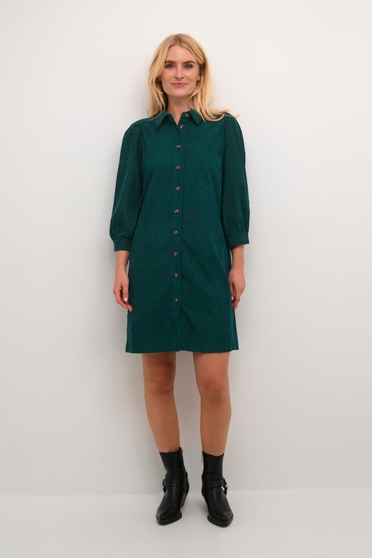 Hemdblusenkleid mit geradem Schnitt, spitzem Kragen, 3/4-Ärmeln mit sanfter Raffung. Durchgehende Knopfleiste und weiche Textur.