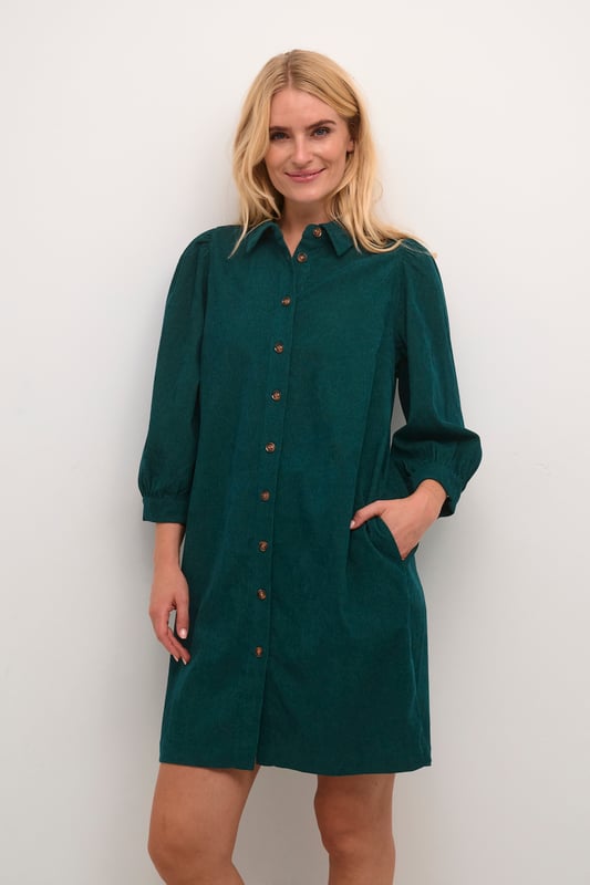 Hemdblusenkleid mit geradem Schnitt, spitzem Kragen, 3/4-Ärmeln mit sanfter Raffung. Durchgehende Knopfleiste und weiche Textur.