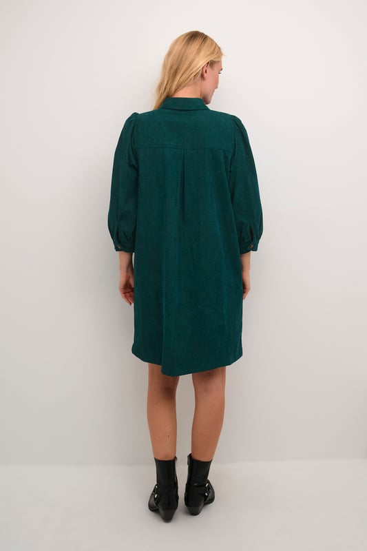 Hemdblusenkleid mit geradem Schnitt, spitzem Kragen, 3/4-Ärmeln mit sanfter Raffung. Durchgehende Knopfleiste und weiche Textur.