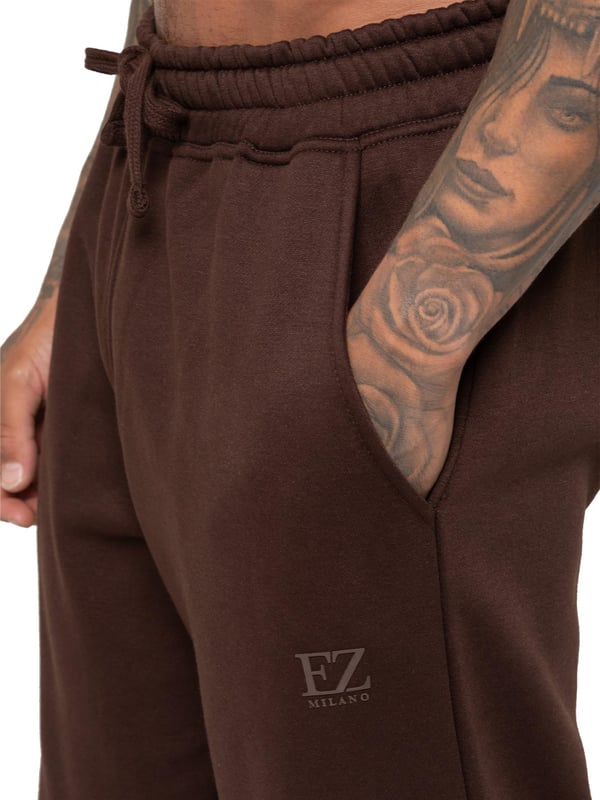 Hergestellt für Komfort und Stil, ist die Enzo Milano Relaxed Fit Open Hem Jogger aus hochwertigem, gebürstetem Fleece-Baumwolle gefertigt und bietet ein weiches, langlebiges und gemütliches Gefühl. Ausgestattet mit einem schweren, ribbestrickten elastischen Bund und verstellbaren Kordeln sorgt sie für einen sicheren und zugleich flexiblen Sitz. Mit zwei Seitentaschen und einer Gesäßtasche kombiniert sie Praktikabilität mit einem eleganten Design. Die gerade Silhouette mit einem sauber genähten Saum sorgt für einen modernen, lässigen Look. Abgerundet wird das Ganze durch den charakteristischen ENZO MILANO Gummidruck am linken Bein.