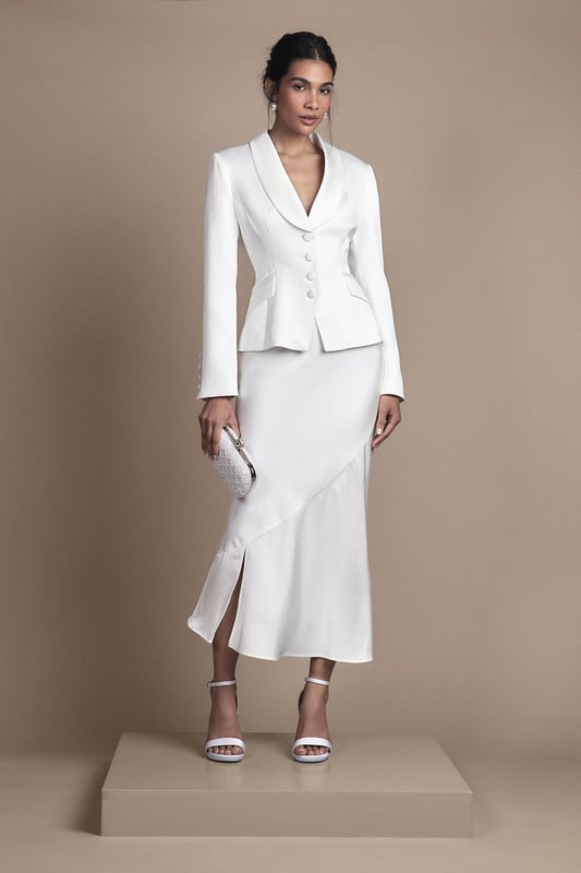 Elegant fitted skirt with luxurious satin detailing for a sophisticated bridal aesthetic
        Flattering midi length with a contemporary side split for graceful movement
        Sleek silhouette that contours to your figure with a subtle flare towards the hem
        Versatile design that pairs beautifully with the matching tailored jacket for a complete bridal ensemble
        Thoughtful construction with a comfortable stretch element for ease of wear throughout your special day
    
    This exquisitely crafted fitted skirt from Coast embodies timeless bridal elegance with modern sensibility. The refined satin detailing adds a subtle lustre to the structured silhouette, while the contemporary side split ensures you can move with grace and poise throughout your wedding celebrations. Style with the coordinating tailored jacket for a sophisticated bridal look that reflects classic tailoring with a contemporary twist. For a complete ensemble, pair with delicate strappy heels and a clutch bag as shown. The midi length offers a refined alternative to traditional bridal wear, making it perfect for registry ceremonies, intimate weddings, or as a stunning outfit change for evening receptions. This versatile piece transitions beautifully from the ceremony to celebration, ensuring you feel confident and elegant on your most treasured day.