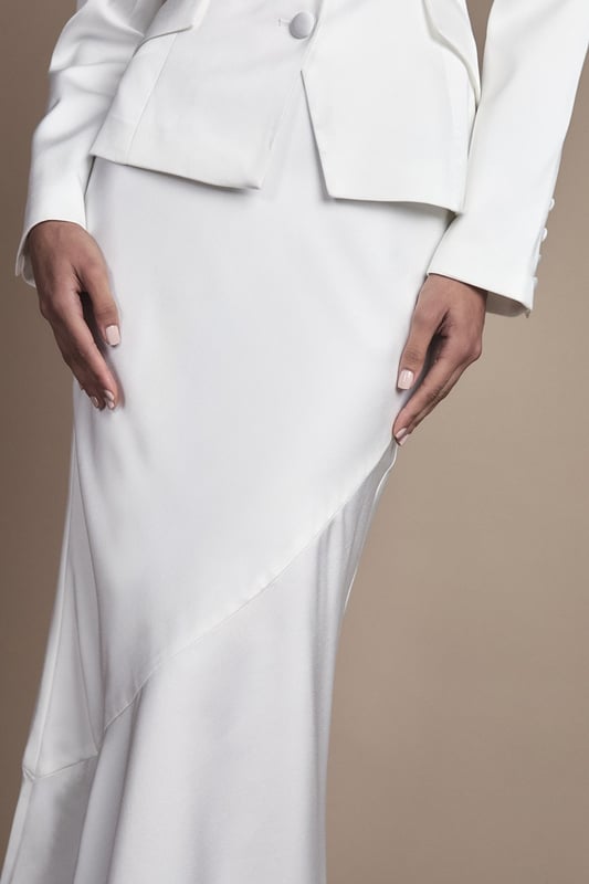 Elegant fitted skirt with luxurious satin detailing for a sophisticated bridal aesthetic
        Flattering midi length with a contemporary side split for graceful movement
        Sleek silhouette that contours to your figure with a subtle flare towards the hem
        Versatile design that pairs beautifully with the matching tailored jacket for a complete bridal ensemble
        Thoughtful construction with a comfortable stretch element for ease of wear throughout your special day
    
    This exquisitely crafted fitted skirt from Coast embodies timeless bridal elegance with modern sensibility. The refined satin detailing adds a subtle lustre to the structured silhouette, while the contemporary side split ensures you can move with grace and poise throughout your wedding celebrations. Style with the coordinating tailored jacket for a sophisticated bridal look that reflects classic tailoring with a contemporary twist. For a complete ensemble, pair with delicate strappy heels and a clutch bag as shown. The midi length offers a refined alternative to traditional bridal wear, making it perfect for registry ceremonies, intimate weddings, or as a stunning outfit change for evening receptions. This versatile piece transitions beautifully from the ceremony to celebration, ensuring you feel confident and elegant on your most treasured day.