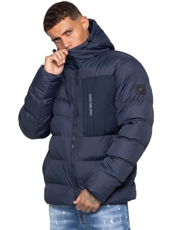 Bleiben Sie warm und stilvoll mit der Enzo Milano Herren Pufferjacke, die aus wasserabweisendem Material gefertigt ist, um Sie vor leichtem Regen und Wind zu schützen. Sie ist mit einer Brusttasche, zwei mit Reißverschluss versehenen Seitentaschen und einer einzelnen Innentasche mit Reißverschluss ausgestattet. Die charakteristische Enzo Milano Markenwerbung, einschließlich eines Metallabzeichens am Arm und einem Brustdruck, verleiht einen hochwertigen Touch. Die verstellbare Kordelzugkapuze und der Saum ermöglichen eine individuelle Passform, was diese Pufferjacke zu einer vielseitigen Wahl für den Alltag macht.