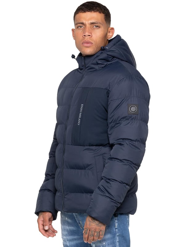 Bleiben Sie warm und stilvoll mit der Enzo Milano Herren Pufferjacke, die aus wasserabweisendem Material gefertigt ist, um Sie vor leichtem Regen und Wind zu schützen. Sie ist mit einer Brusttasche, zwei mit Reißverschluss versehenen Seitentaschen und einer einzelnen Innentasche mit Reißverschluss ausgestattet. Die charakteristische Enzo Milano Markenwerbung, einschließlich eines Metallabzeichens am Arm und einem Brustdruck, verleiht einen hochwertigen Touch. Die verstellbare Kordelzugkapuze und der Saum ermöglichen eine individuelle Passform, was diese Pufferjacke zu einer vielseitigen Wahl für den Alltag macht.