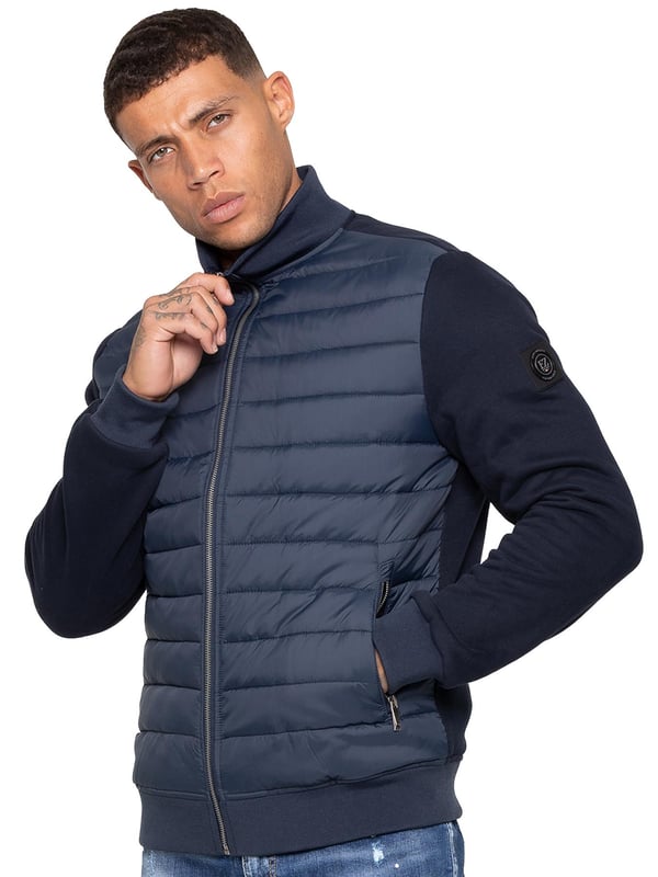Verhoog je buitenkleding met de Enzo Milano Mannen Hybride Jas. Voorzien van een geribbelde kraag en een gewatteerd, waterafstotend polyamide voorpaneel. Het katoenen jersey rugpaneel en de mouwen zorgen voor flexibiliteit en ademend vermogen, terwijl geribbelde manchetten en een omgeslagen zoom een veilige pasvorm creëren. Praktische details zijn onder andere twee zijzakken met rits en opbergmogelijkheden aan de binnenkant. Afgewerkt met de kenmerkende Enzo Milano metalen badge op de linkerarm. (MJK47)