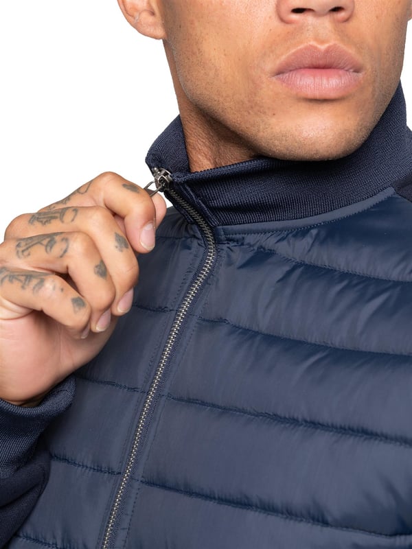 Verhoog je buitenkleding met de Enzo Milano Mannen Hybride Jas. Voorzien van een geribbelde kraag en een gewatteerd, waterafstotend polyamide voorpaneel. Het katoenen jersey rugpaneel en de mouwen zorgen voor flexibiliteit en ademend vermogen, terwijl geribbelde manchetten en een omgeslagen zoom een veilige pasvorm creëren. Praktische details zijn onder andere twee zijzakken met rits en opbergmogelijkheden aan de binnenkant. Afgewerkt met de kenmerkende Enzo Milano metalen badge op de linkerarm. (MJK47)