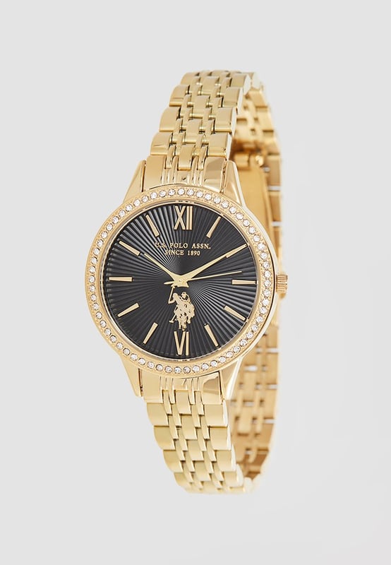 Quarzbewegung (hohe Präzision) 34 mm Metallgehäuse mit Gelbgold-Beschichtung Metalllünette mit Gelbgold-Beschichtung und weißen Kristallen Schwarzes Zifferblatt mit applizierten Indizes S. Stahl Krone / S. Stahl Gehäuseboden Hoch widerstandsfähiges Mineralglas S. Stahl Armband mit Gelbgold-Beschichtung und personalisierter Schließe Wasserfest bis 3 ATM