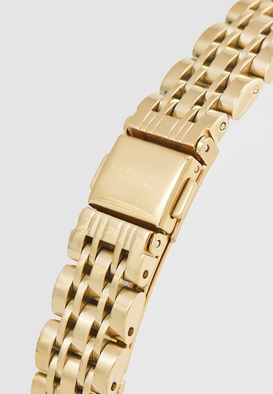 Quarzbewegung (hohe Präzision) 34 mm Metallgehäuse mit Gelbgold-Beschichtung Metalllünette mit Gelbgold-Beschichtung und weißen Kristallen Schwarzes Zifferblatt mit applizierten Indizes S. Stahl Krone / S. Stahl Gehäuseboden Hoch widerstandsfähiges Mineralglas S. Stahl Armband mit Gelbgold-Beschichtung und personalisierter Schließe Wasserfest bis 3 ATM