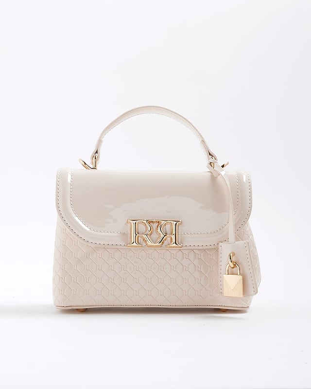 River Island Womens Tote Bag Cream Patent RI Flap Patent, RI monogram print, Grab handle, Detachable cross body strap, Charm detail, Gold branding, Interior zipped compartment, Front flap closure, Strap length: 60cm, H: 16cm x W: 24cm x D: 10cm