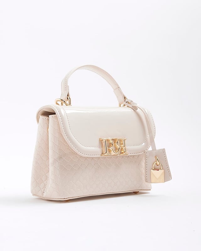 River Island Womens Tote Bag Cream Patent RI Flap Patent, RI monogram print, Grab handle, Detachable cross body strap, Charm detail, Gold branding, Interior zipped compartment, Front flap closure, Strap length: 60cm, H: 16cm x W: 24cm x D: 10cm