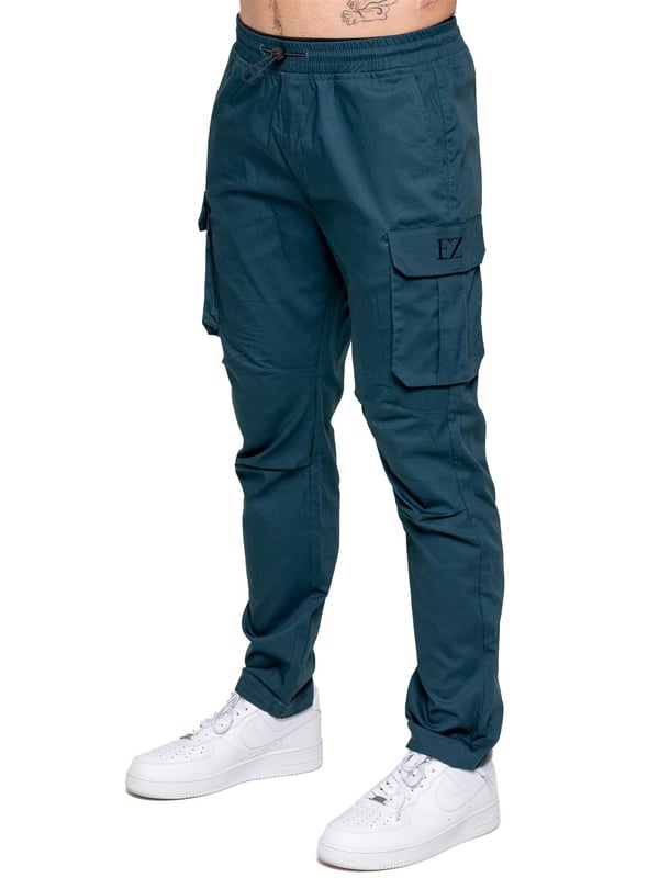 Bringe deinen Alltagsstil auf das nächste Level mit der Enzo Herren-Cargohose. Gefertigt aus hochwertigem Stretchstoff, bietet diese leichte Hose eine schmal zulaufende Passform für einen eleganten, modernen Look. Der elastische Bund mit verstellbarem Kordelzug ermöglicht eine individuelle Passform, während die verstellbaren Kordelzüge an den Knöcheln das Aussehen und Tragegefühl anpassbar machen. Mit zwei seitlichen Eingrifftaschen, zwei Cargotaschen mit sicherem Klettverschluss und einer einzelnen Paspeltasche hinten hast du ausreichend Platz für deine Essentials. Abgerundet mit einem Enzo-Print auf der Cargotasche.