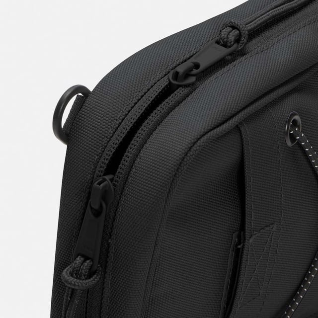 Mens Timberland Crossbody Bag in black.- Large zipper opening into main compartment.- Front panel slip pocket with bungee system and reflective details.- Adjustable shoulder strap.- Mesh back panel.- 2 ways of wearing.- Woven stacked logo badge.- Ref: A5SSY0011