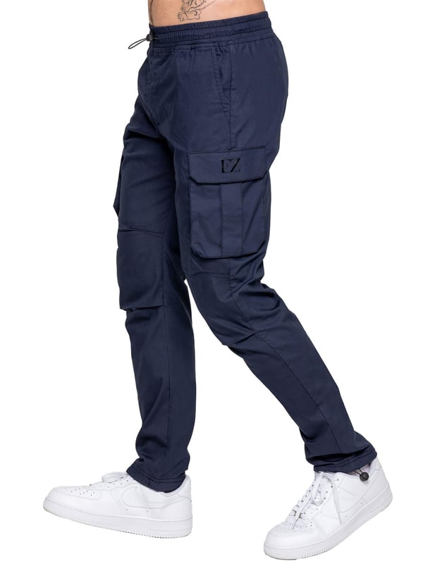 Upgrade your everyday style with the Enzo Men's Cargo Pants. Crafted from premium stretch fabric, these lightweight trousers offer a tapered leg fit for a sleek, modern look. Featuring an elasticated waistband with an adjustable toggle, they provide a customizable fit, while the adjustable toggle ankles let you tailor the look and feel. With two side slash pockets, two cargo pockets with secure Velcro fastening, and a single back welt pocket, you’ll have ample storage for essentials. Finished with an Enzo print on the cargo pocket. (649)